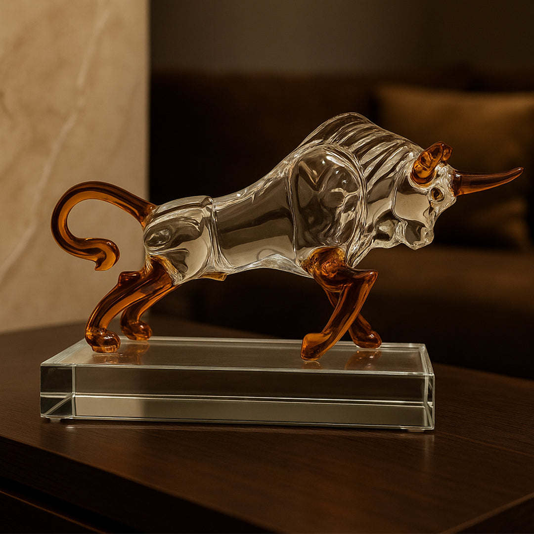 Glass bull figurine with amber accents on a glass base, used for luxury table decor.