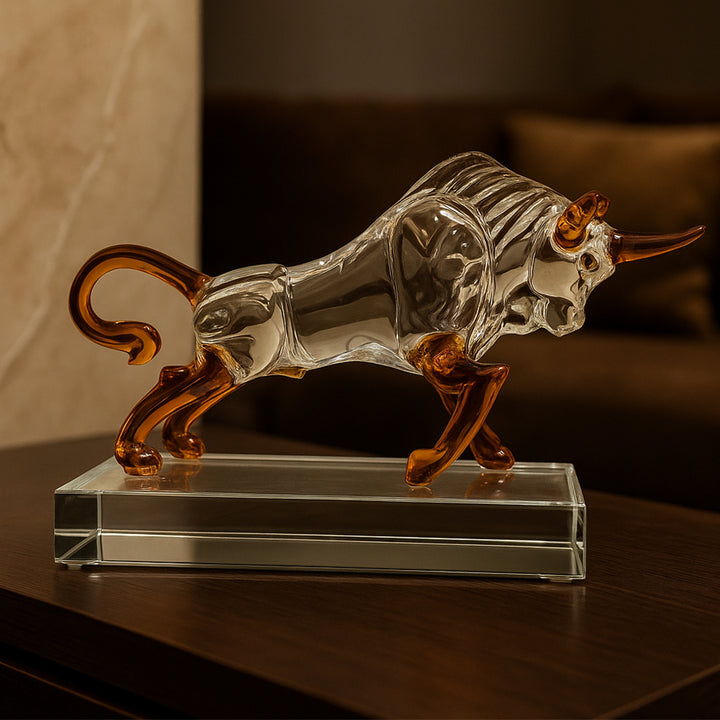 Glass bull figurine with amber accents on a glass base, used for luxury table decor.