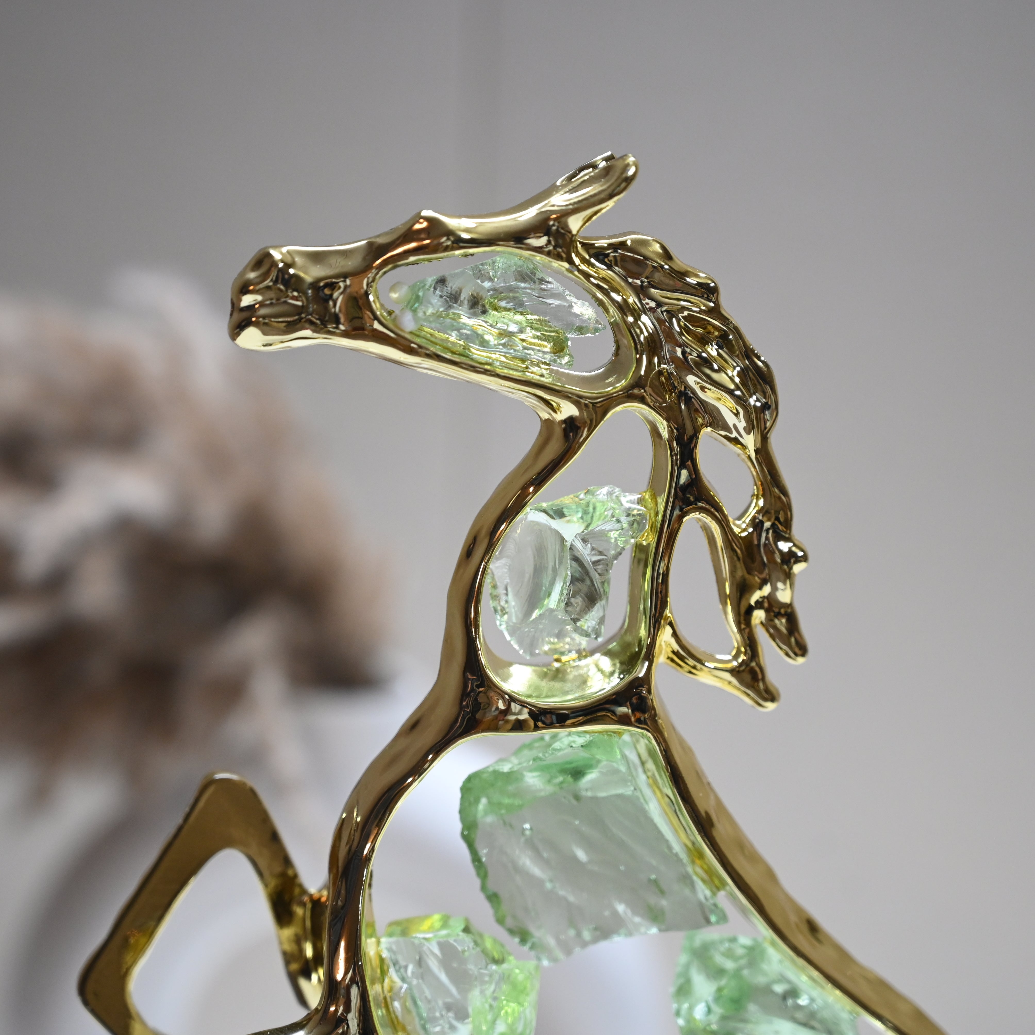 Abstract horse statue with golden frame and green crystals mounted on a black base