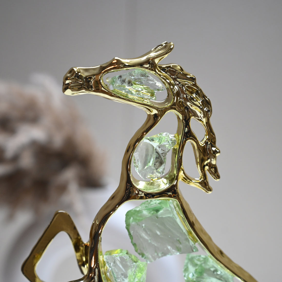 Abstract horse statue with golden frame and green crystals mounted on a black base