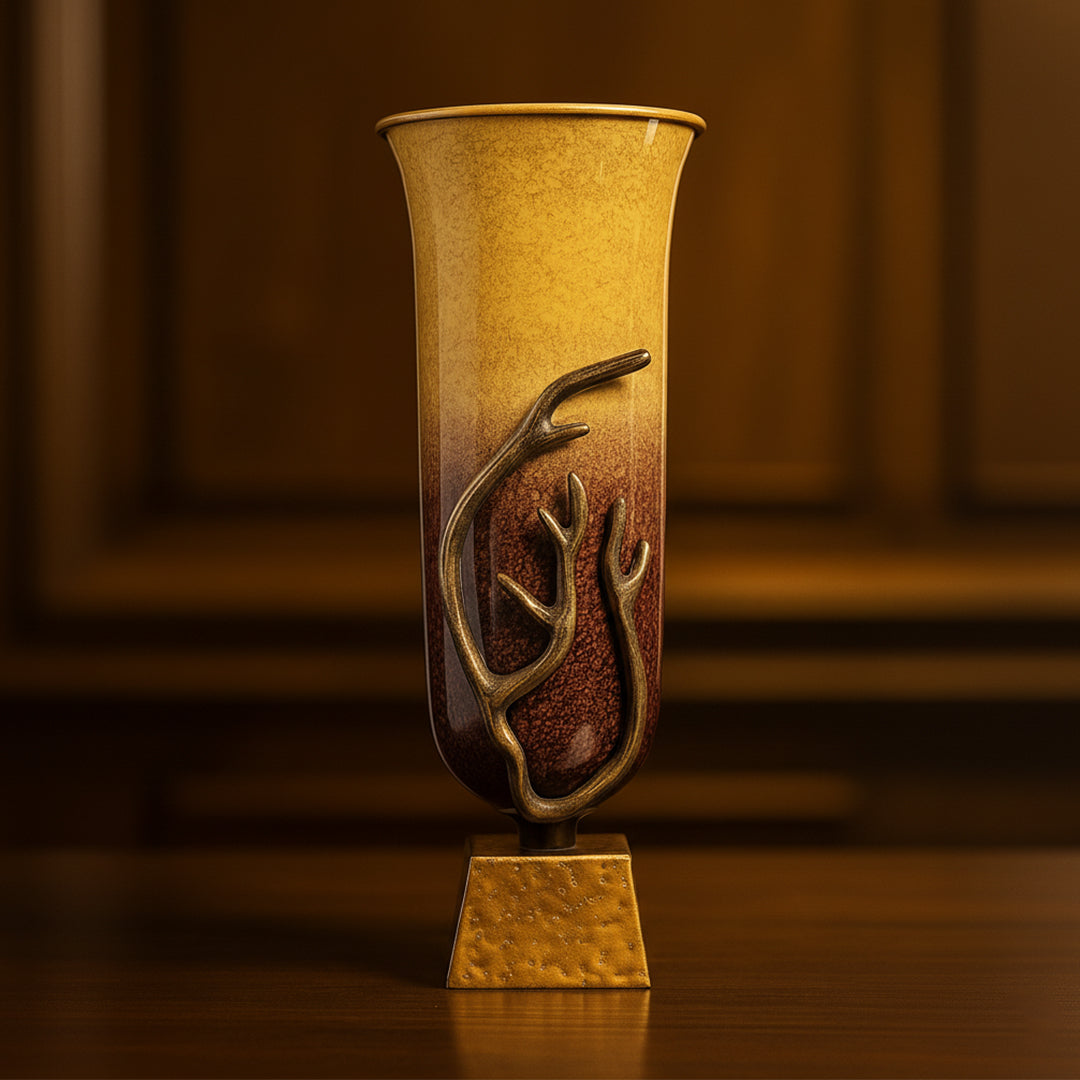 Tall ceramic vase with bronze antler embellishment and ombre brown to gold finish on wood table.
