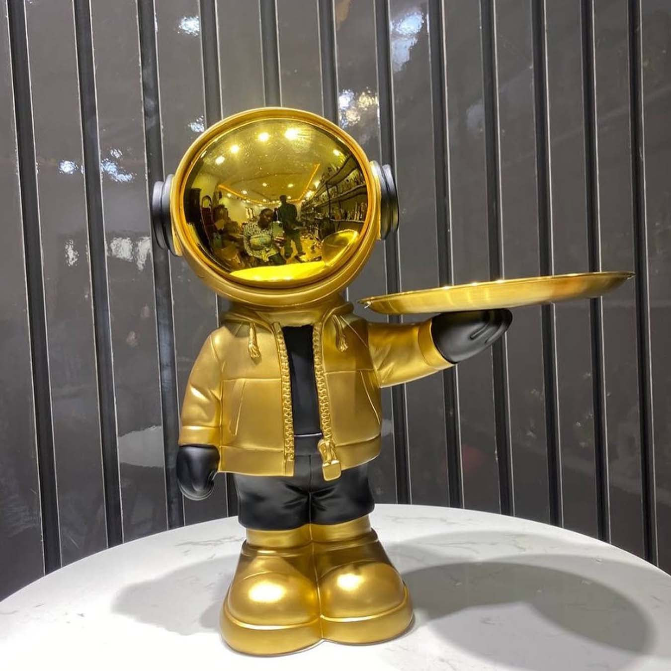 Standing astronaut figure holding a golden tray for decoration"